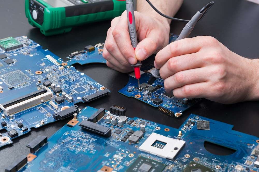 Laptop motherboard testing in service center close-up. Diagnostics of broken computer, electronics repair shop concept